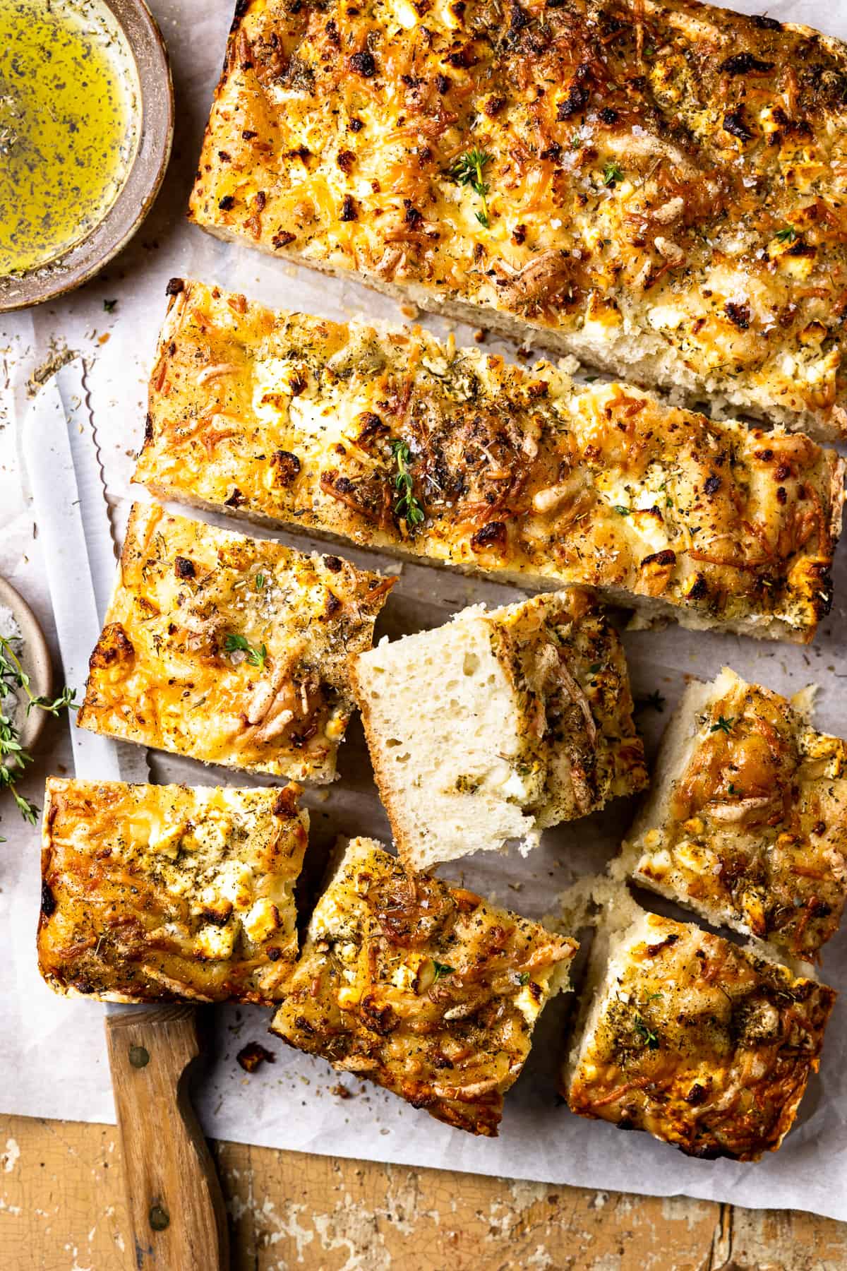 overhead view of no knead focaccia cut into squares with one upturned to show the texture.