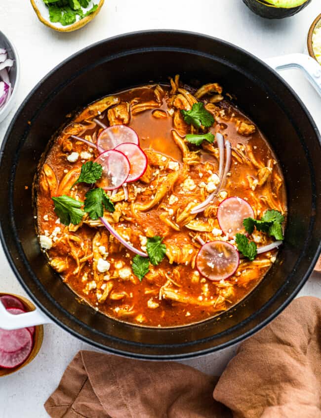 overhead view of chicken tinga in a white and black dutch oven.