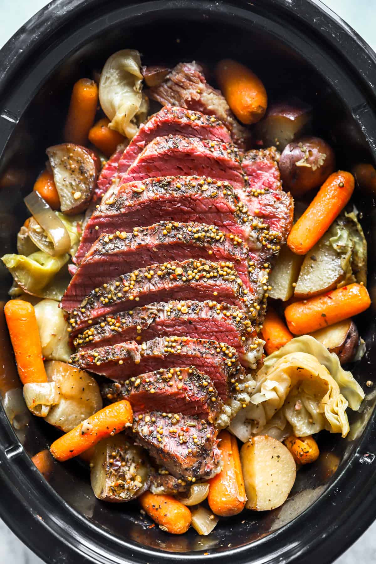 overhead view of sliced crockpot corned beef and cabbage in a crockpot.