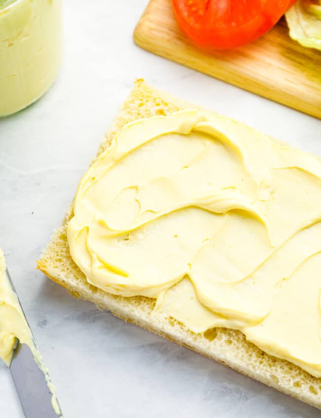 overhead view of mayonnaise slathered on a piece of ciabatta bread.