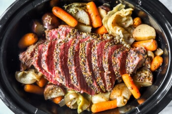 sliced crockpot corned beef and cabbage in a crockpot.