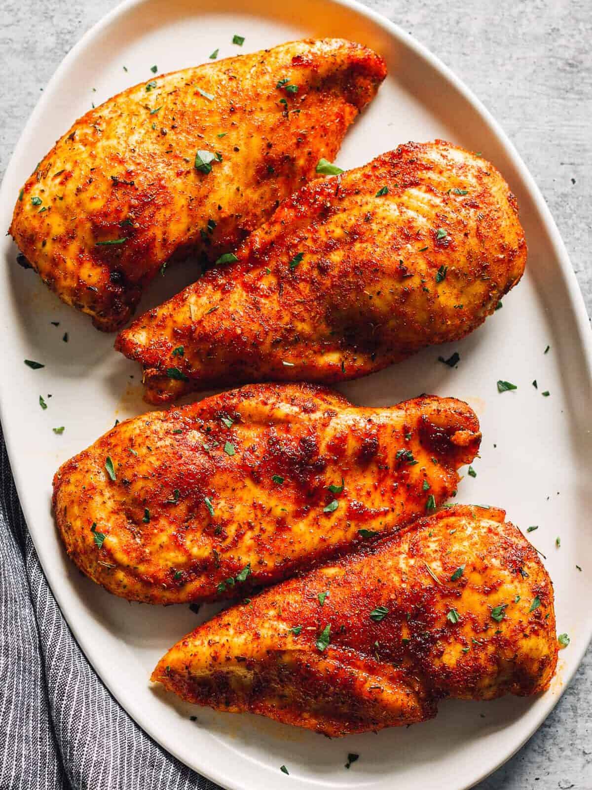 4 seasoned baked chicken breasts on a serving platter