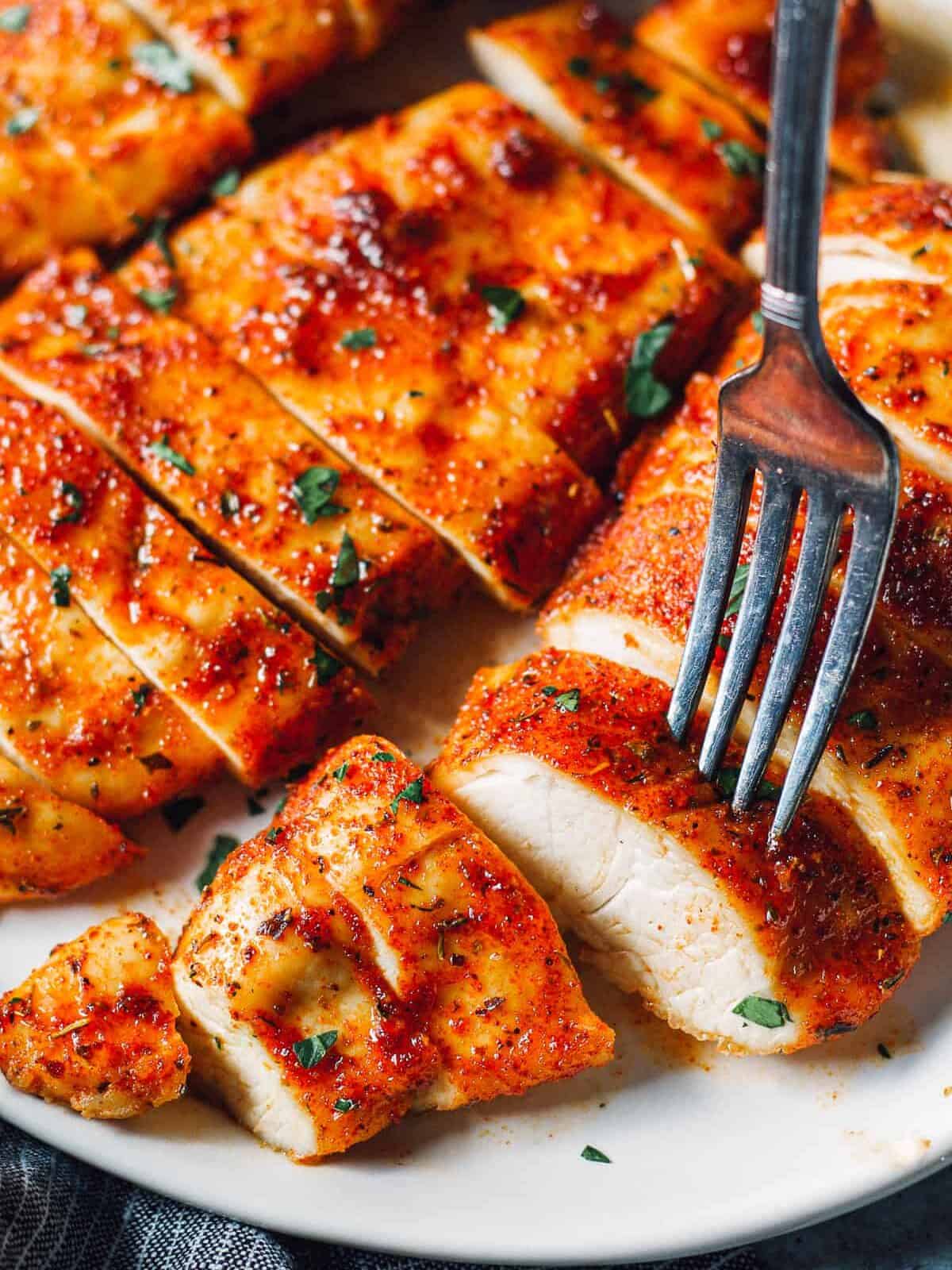 fork piercing into a slice of seasoned baked chicken