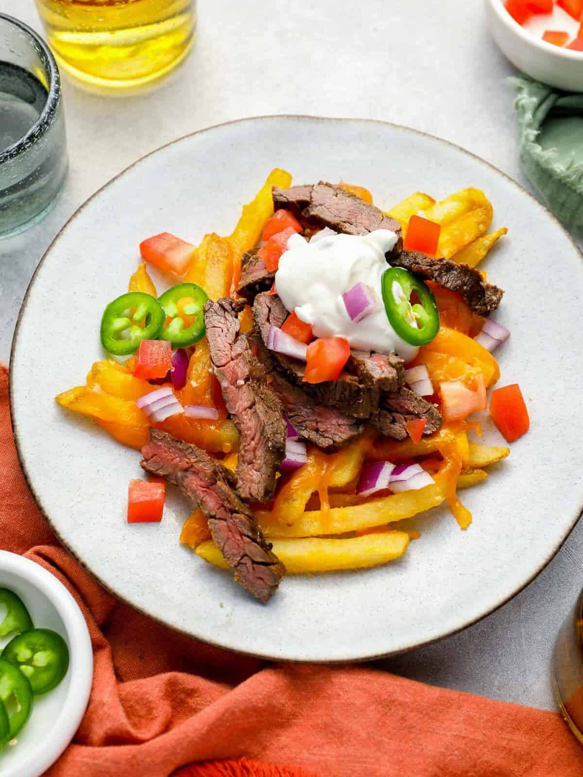 overhead view of a serving of carne asada fries on a white plate.