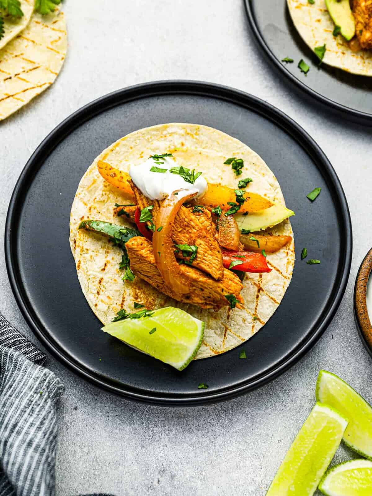 overhead view of chicken fajitas on a on a black plate.