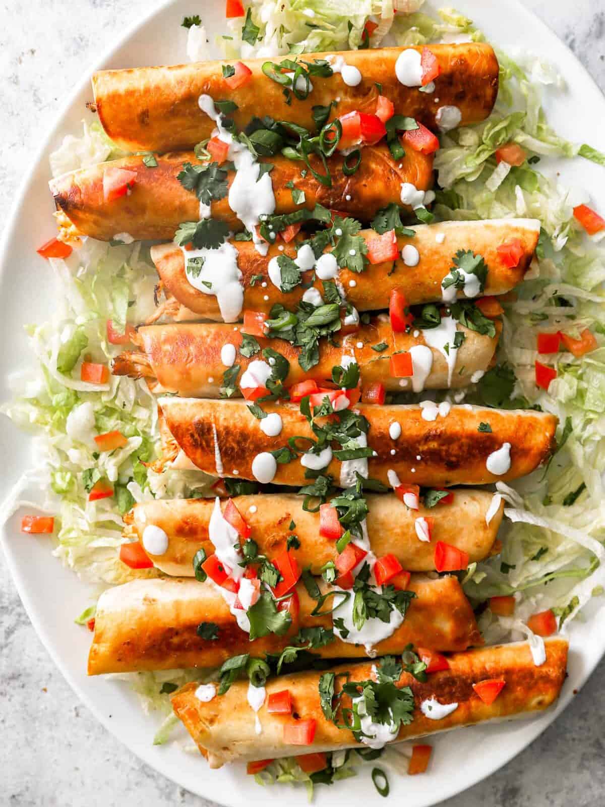 overhead view of 8 chicken flautas on an oval serving platter.