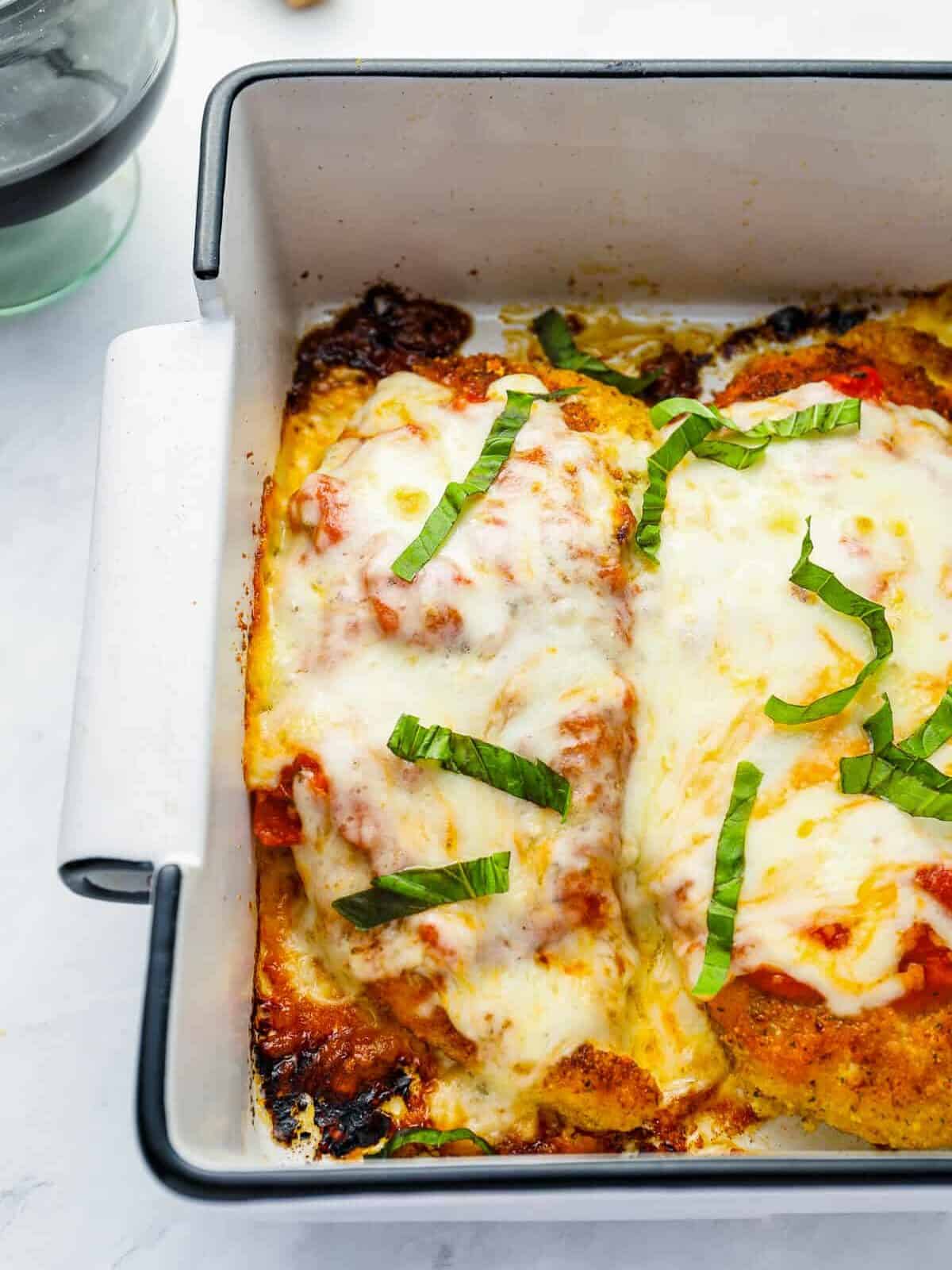 partial view of chicken parmesan in a rectangular white baking pan.