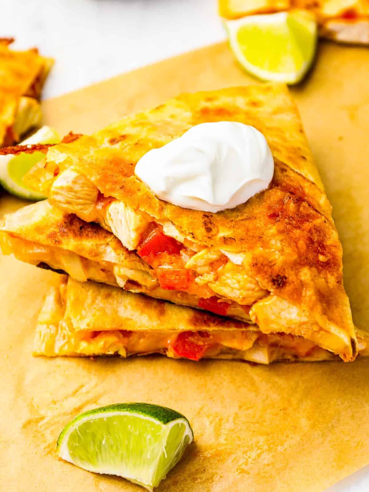 3 stacked slices of chicken quesadillas on parchment paper.