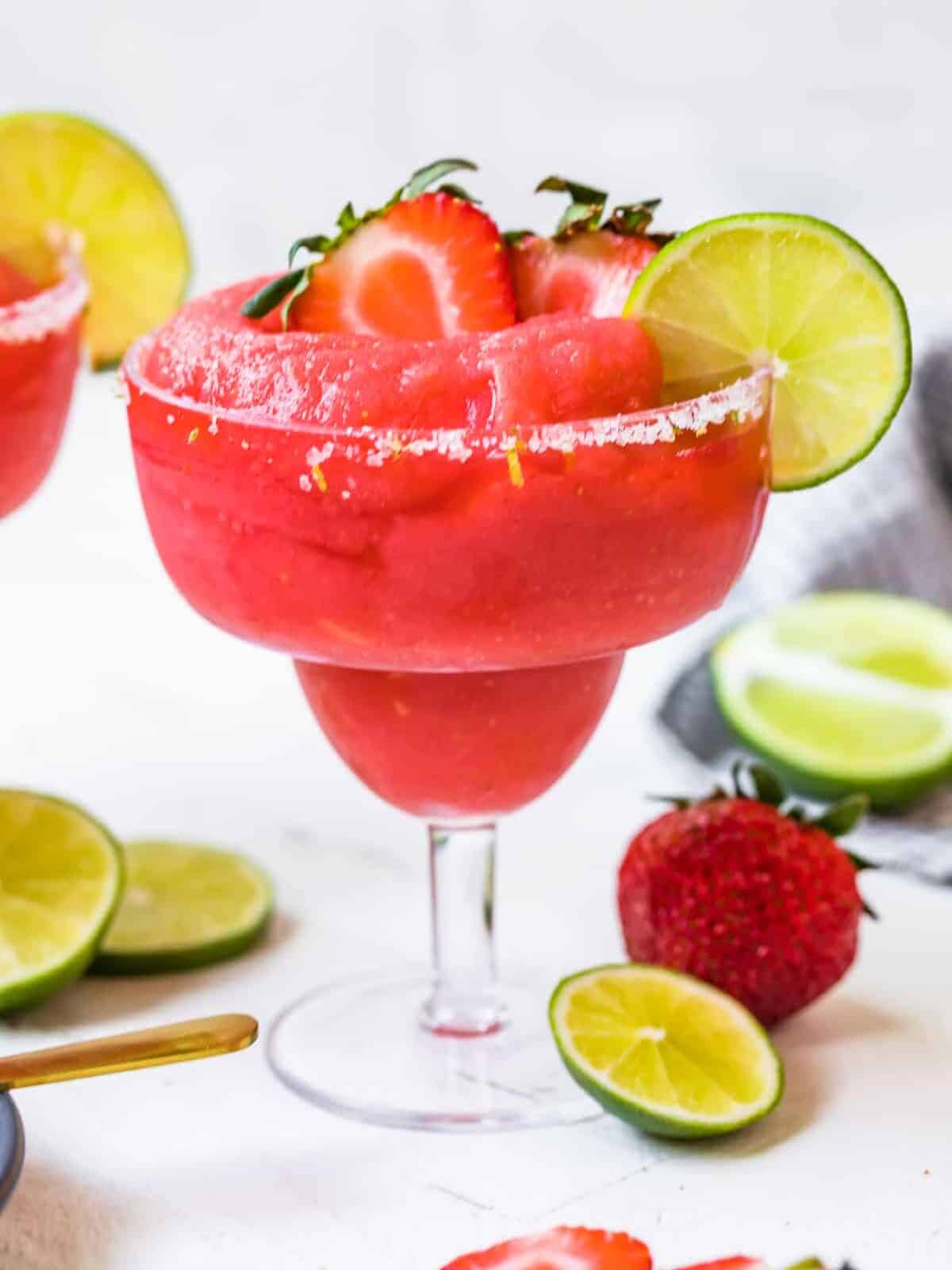 frozen strawberry margaritas garnished with fruit and salt