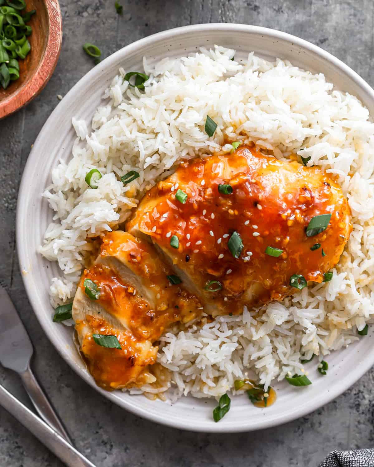 a plate of honey glazed chicken with rice and sauce.