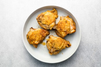 roasted chicken thighs on a white plate.