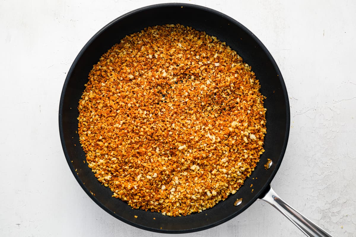 a frying pan filled with toasted breadcrumbs.