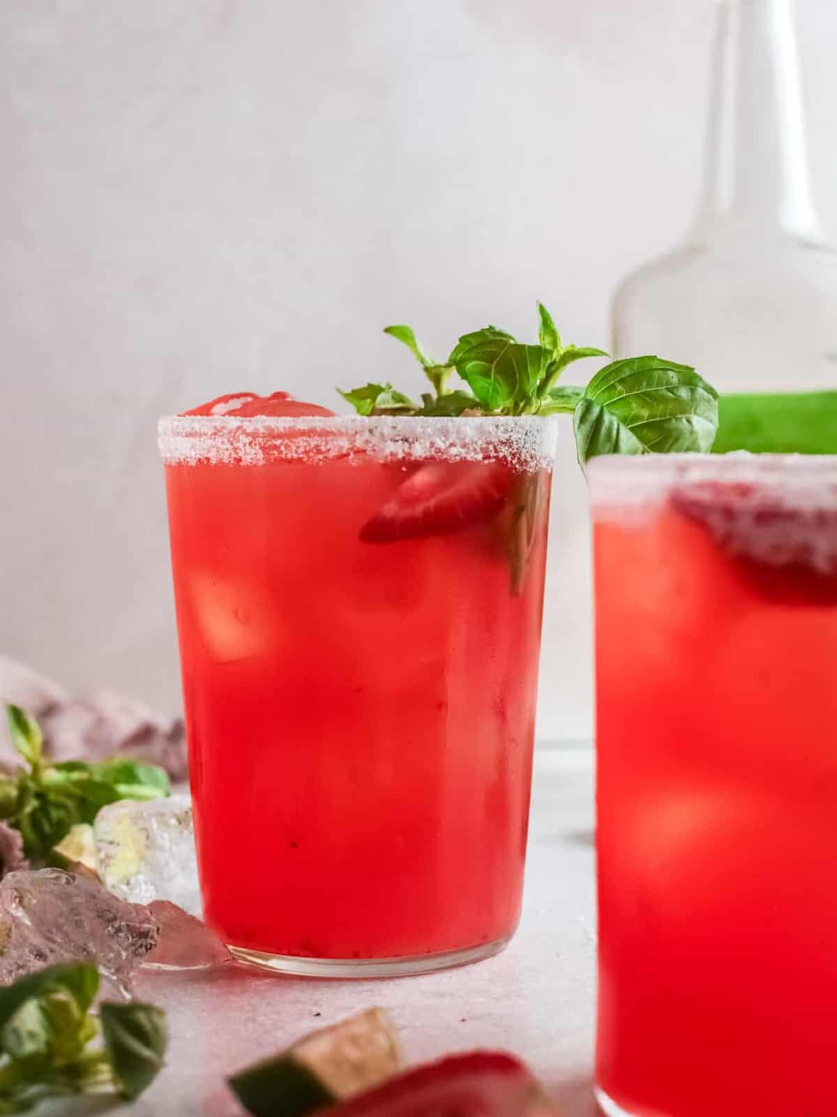 close up of 2 strawberry basil margaritas slightly offset.