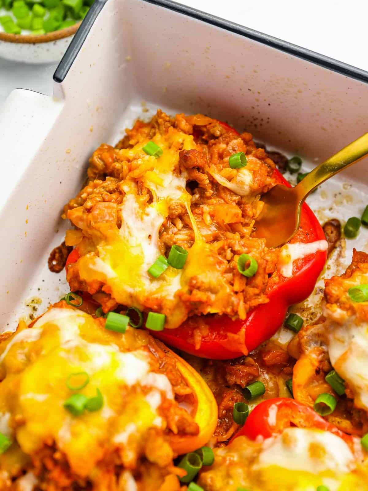 close up of stuffed peppers in a white rectangular baking pan with a fork.