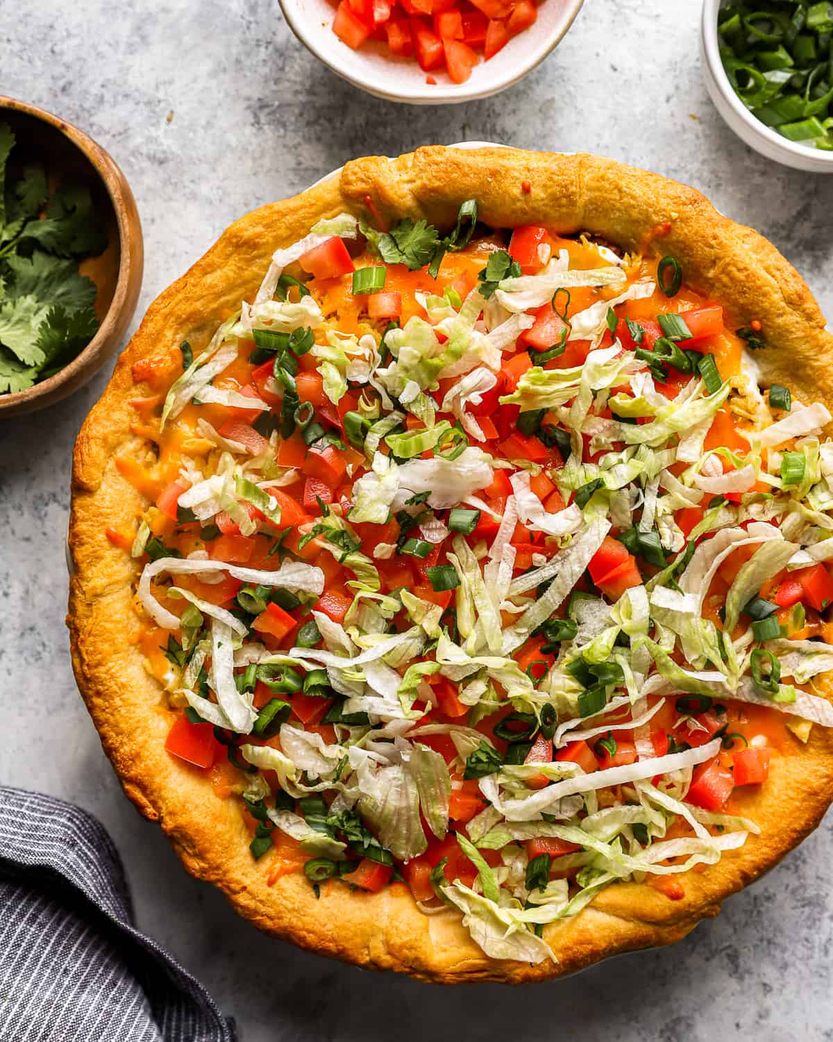 overhead view of crispy taco pie topped with lettuce, green onions, and tomatoes