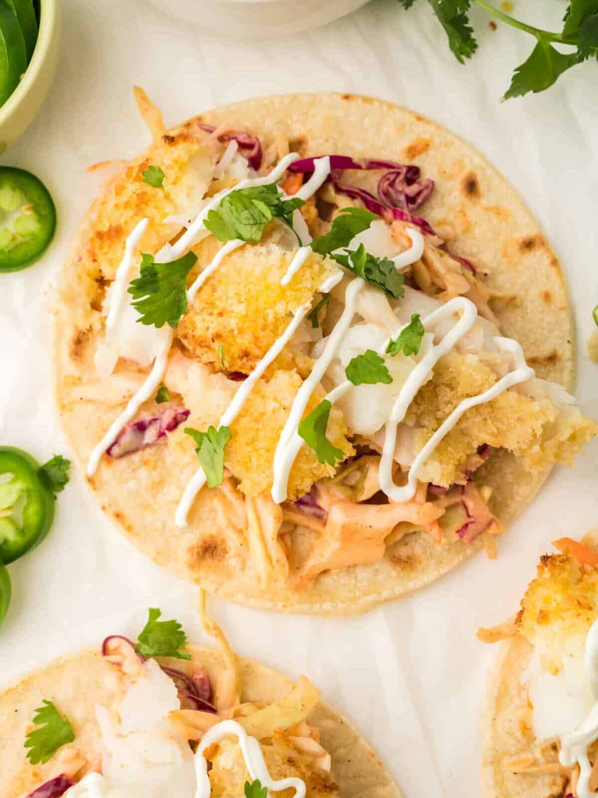 overhead view of a flat air fryer fish taco on a white table.