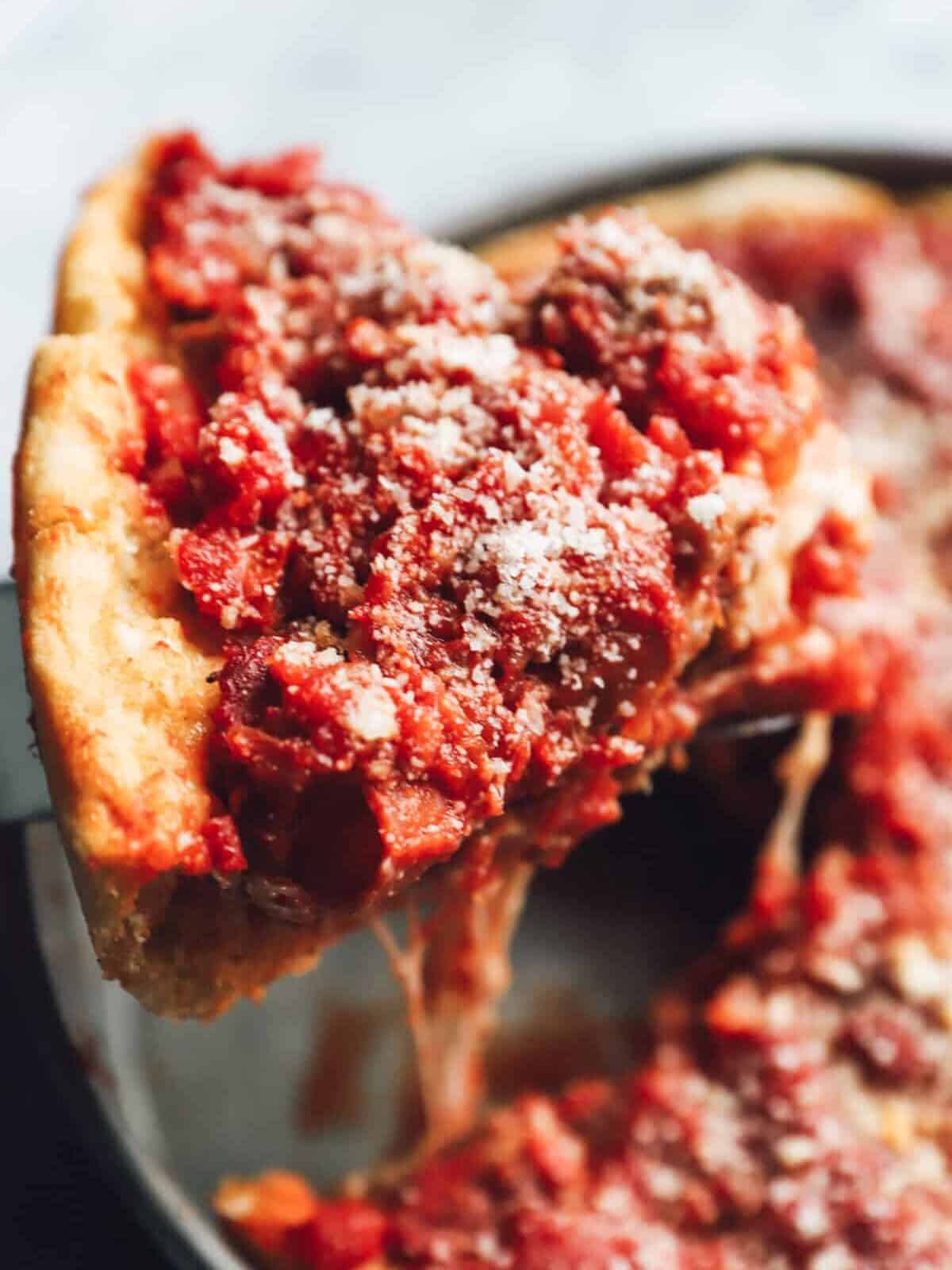 a pie server removing a slice of chicago deep dish pizza from a pan.