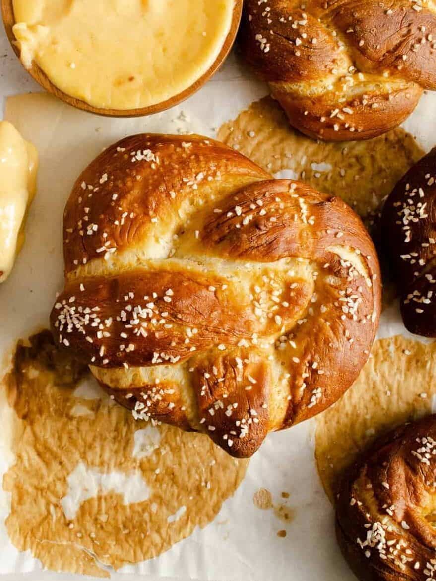 overhead view of homemade pretzels next to a cup of cheese sauce.