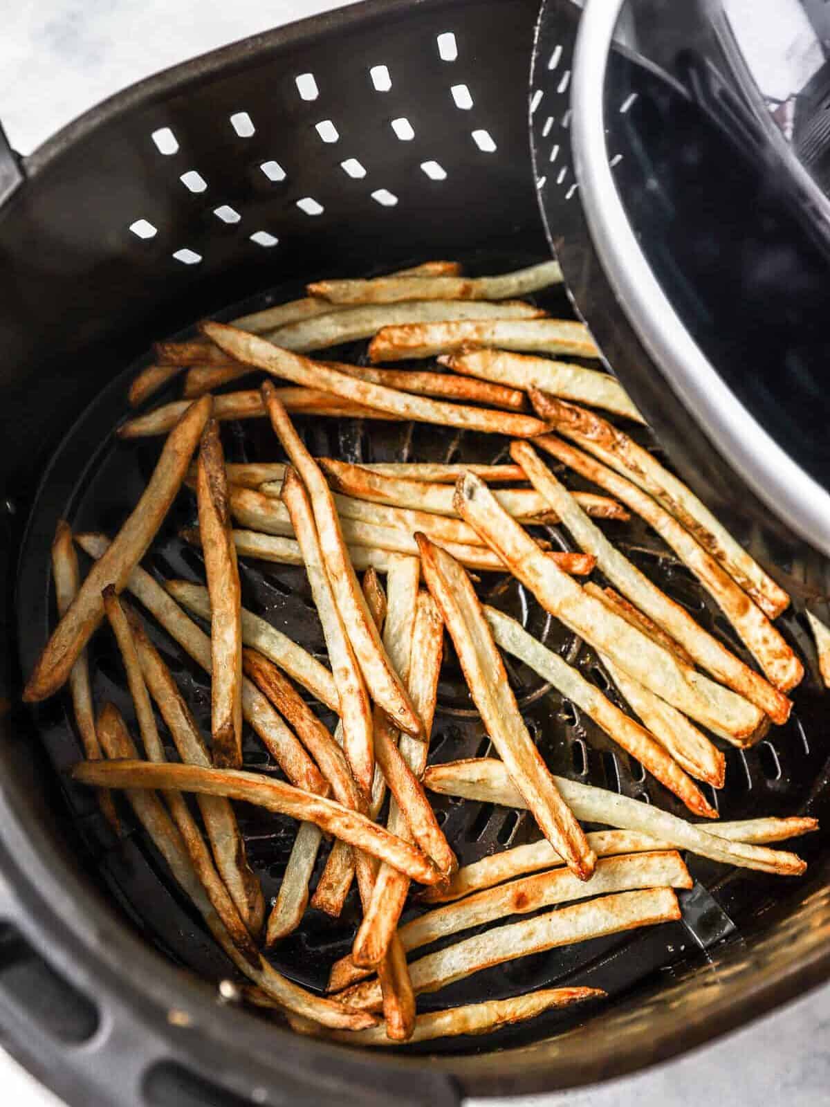 cooked air fryer french fries in an air fryer basket.