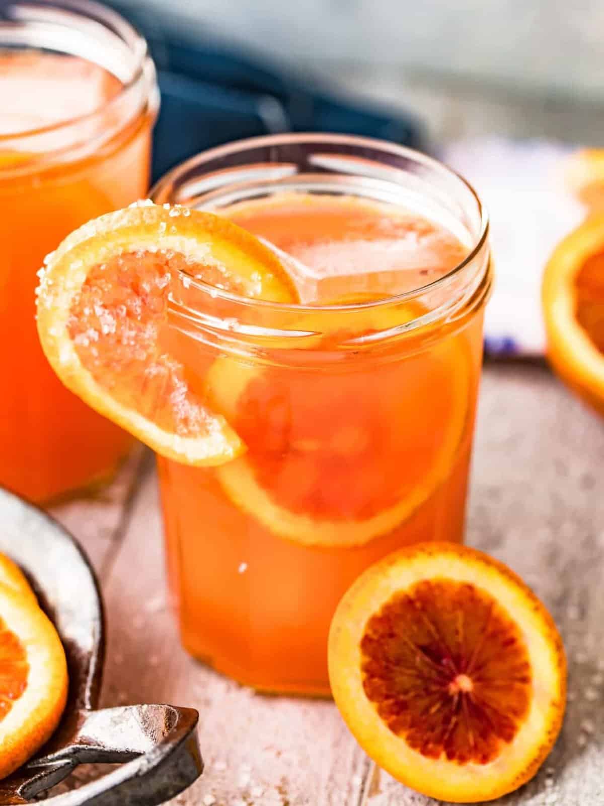 close up a on a blood orange Paloma served in a jar glass and garnished with salted blood oranges