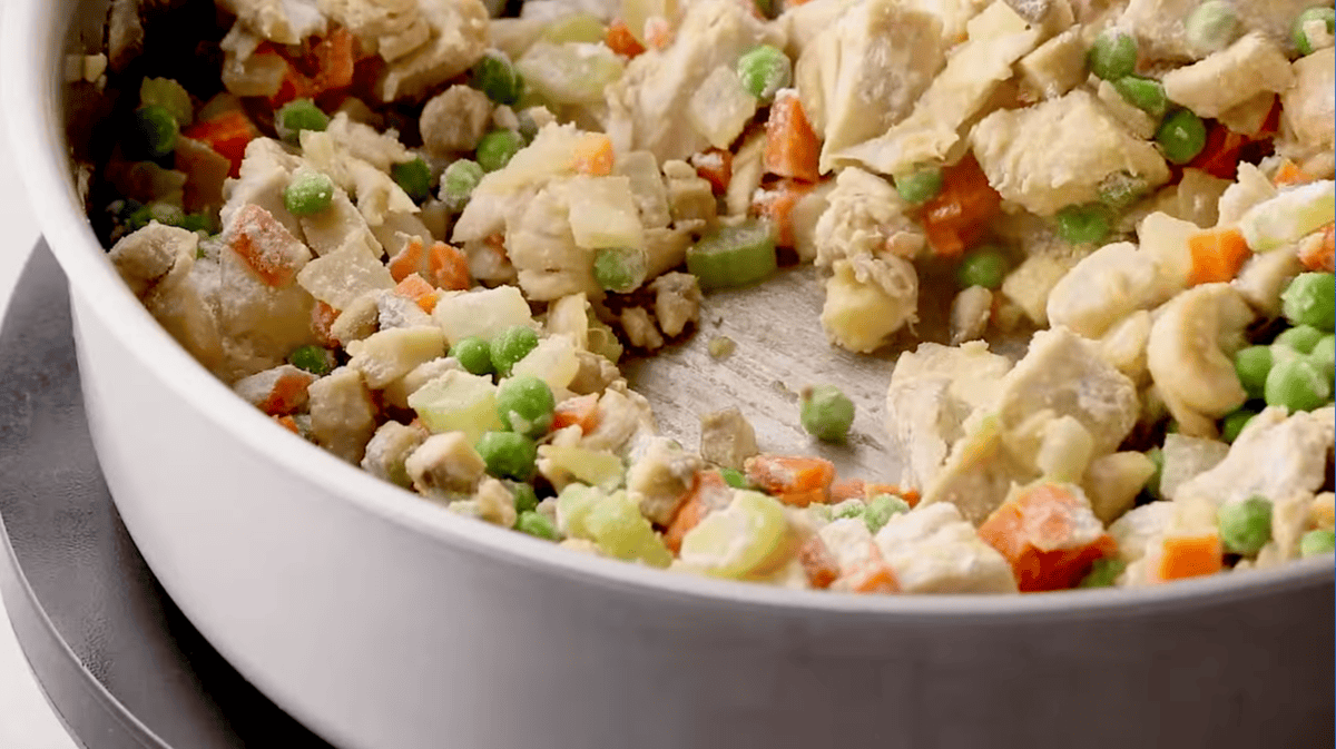 flour coated chicken pot pie filling in a pan.