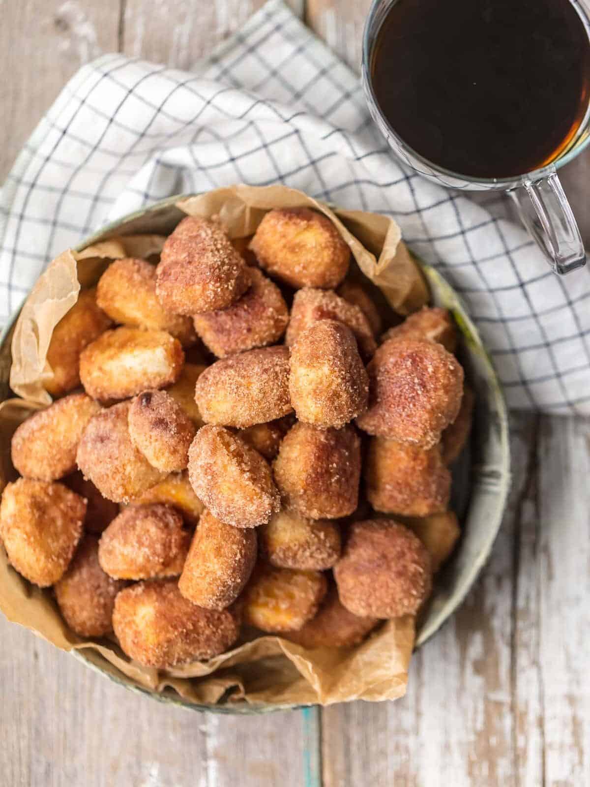 a tray of cinnamon roll bites made with biscuit dough, on a table top with coffee and a dish towel