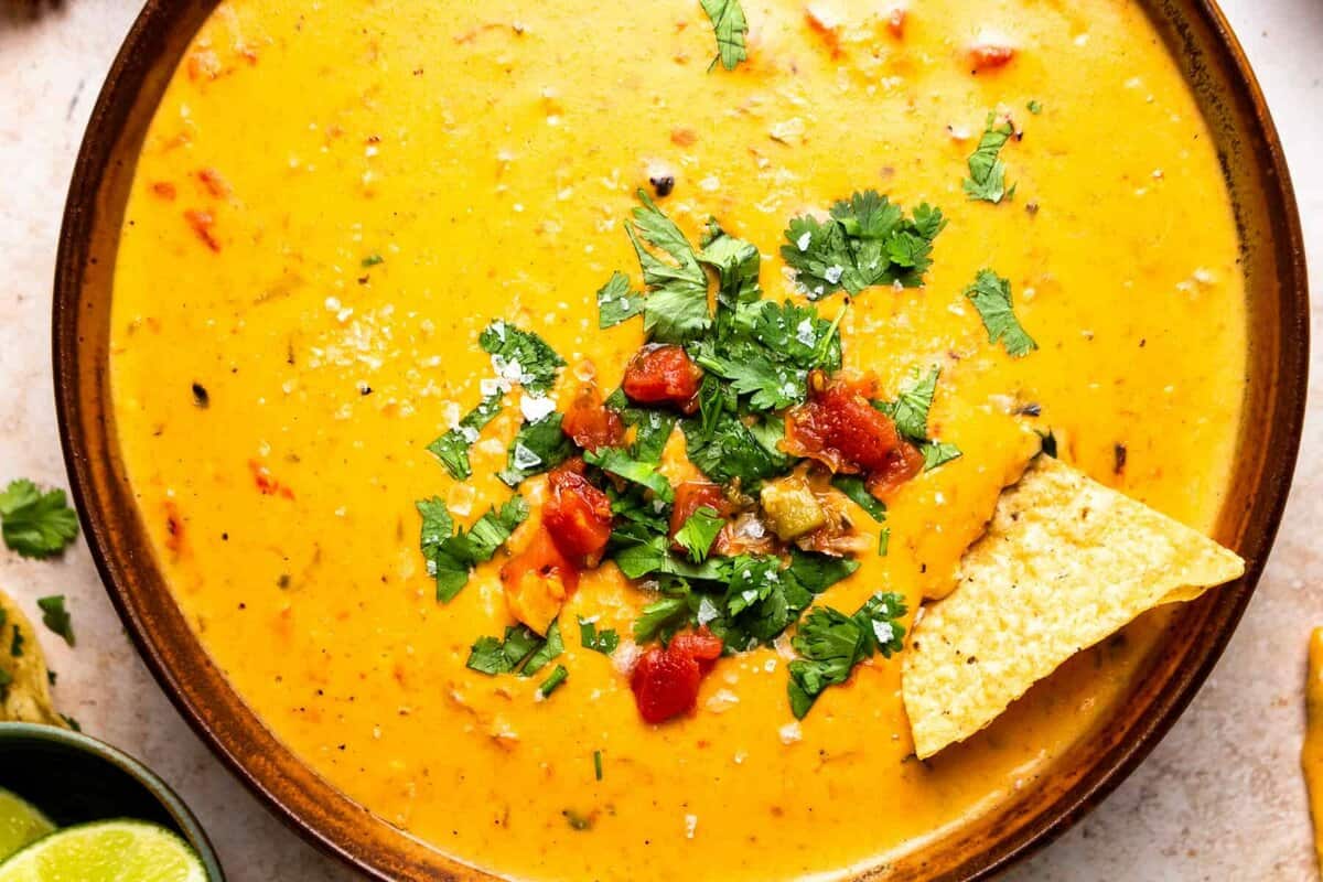 close up on a bowl of slow cooker velveeta queso with a tortilla chip dipped in