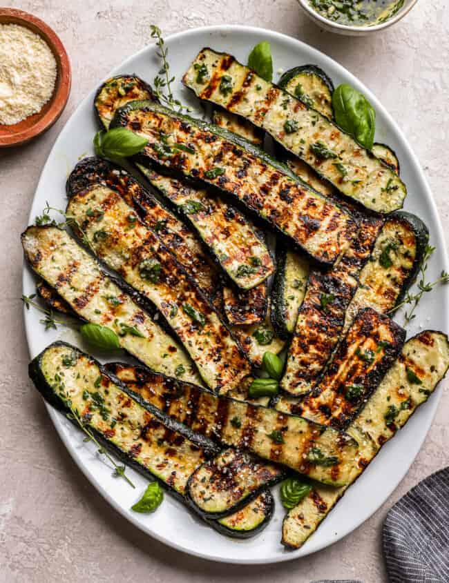 overhead view of grilled zucchini on a white oval plate.