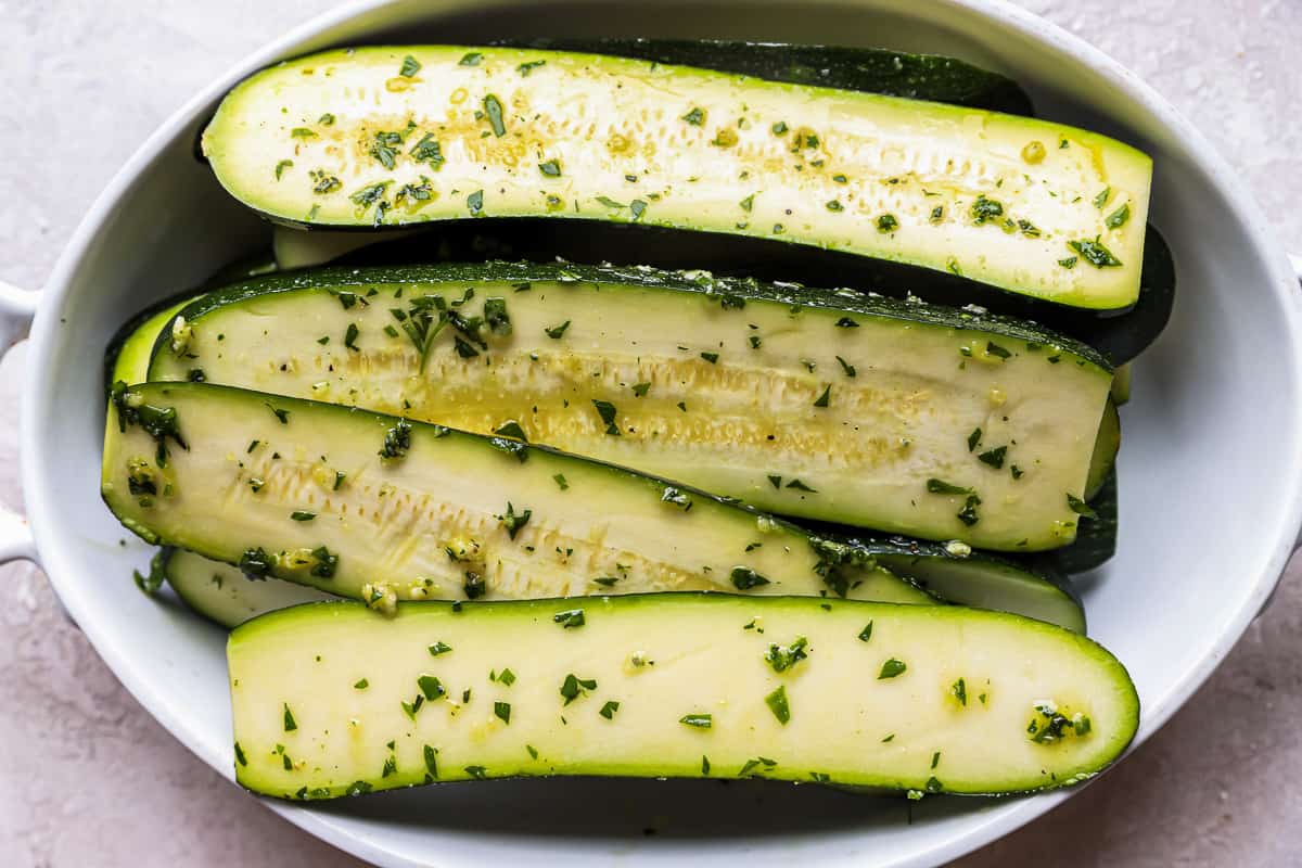 long strips of marinated zucchini in a white bowl.