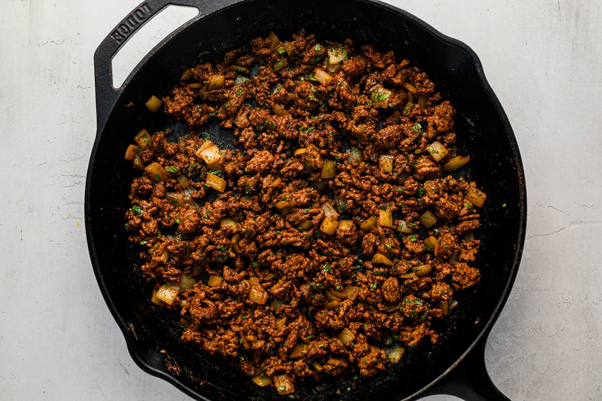 a cast iron skillet filled with meat and onions.