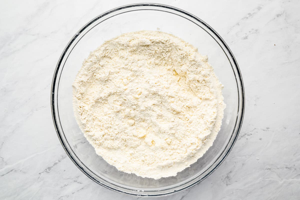 flour in a glass bowl on a marble countertop.