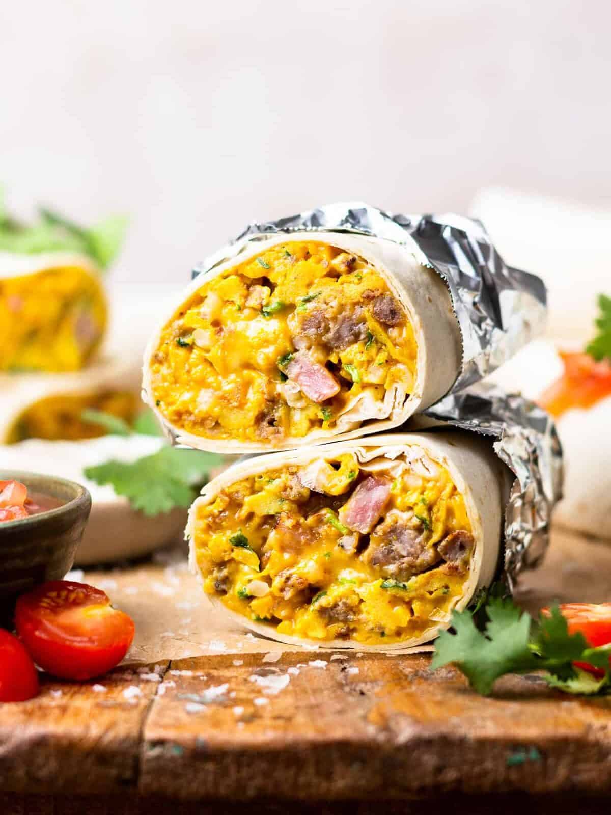 head-on view of a halved make ahead breakfast burrito wrapped in foil on a cutting board.