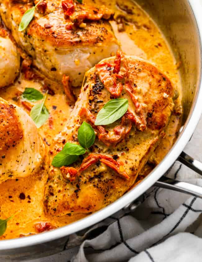 close-up three-quarters view of marry me chicken in a stainless pan.