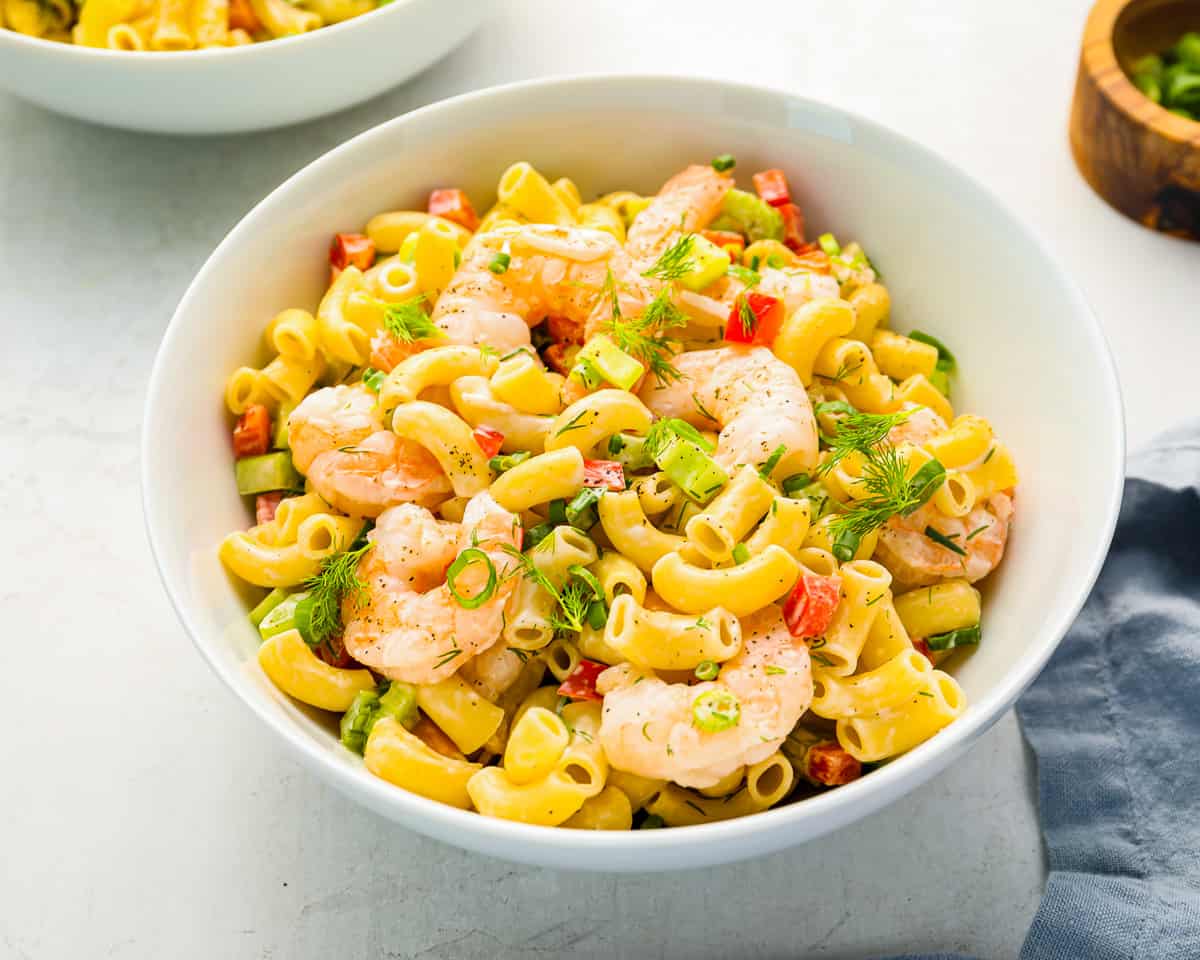 three-quarters view of shrimp pasta salad in a white bowl.