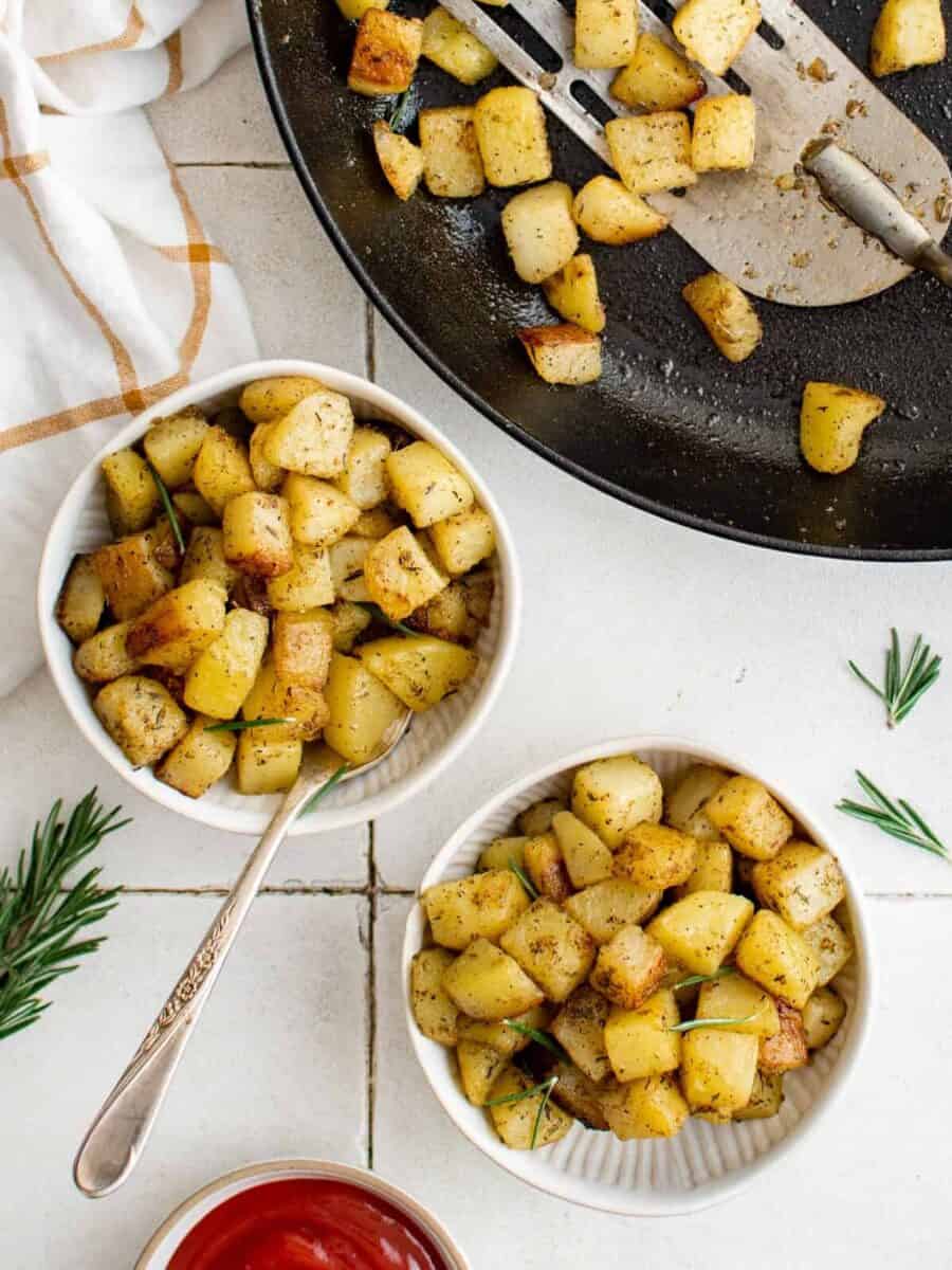 overhead view of servings of breakfast potatoes in white bowls with forks.