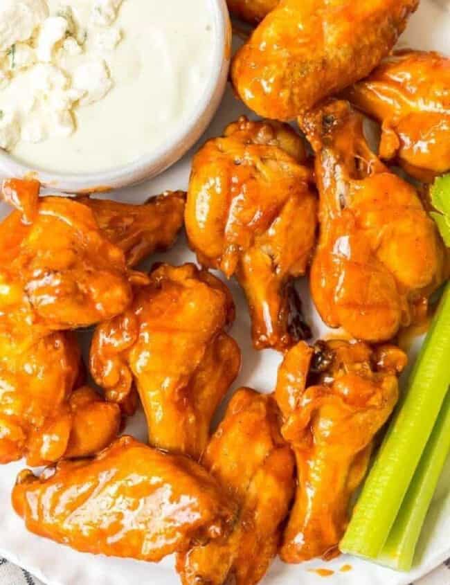 Buffalo wings on a plate with celery and blue cheese dip.