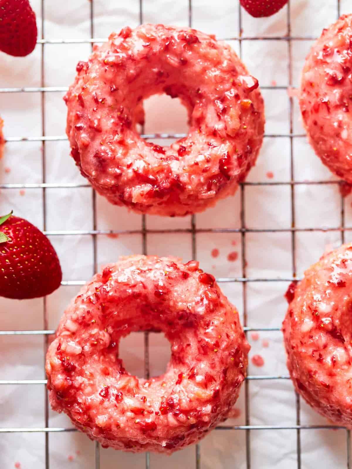 overhead view of strawberry donuts on a wire cooling rack.