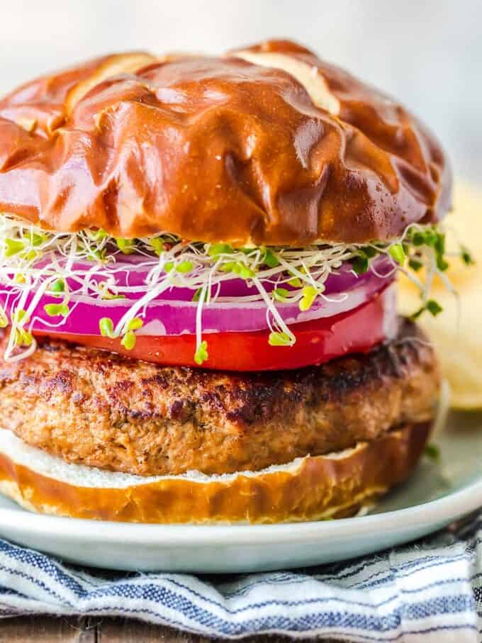 A turkey burger with onions and sprouts on a plate.