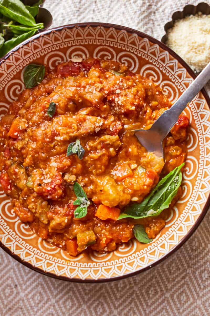 overhead view of a serving of sausage lentil soup in a patterned bowl with a spoon.