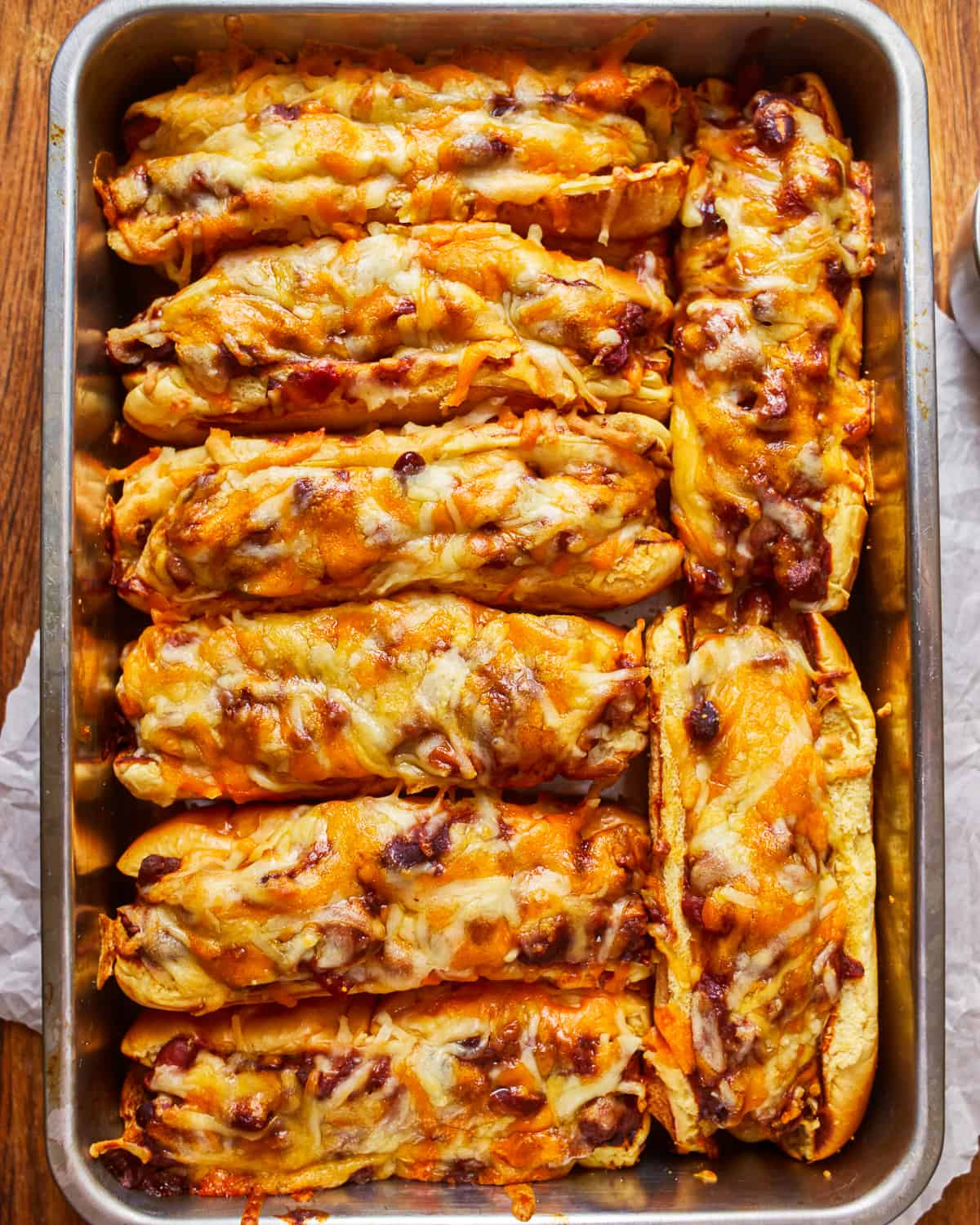 overhead view of 8 chili dogs in a baking pan.