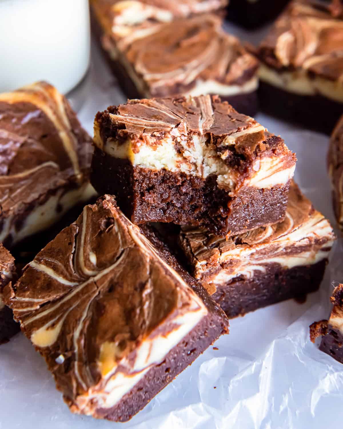 three-quarters view of a bitten cream cheese brownie on top of more brownies.