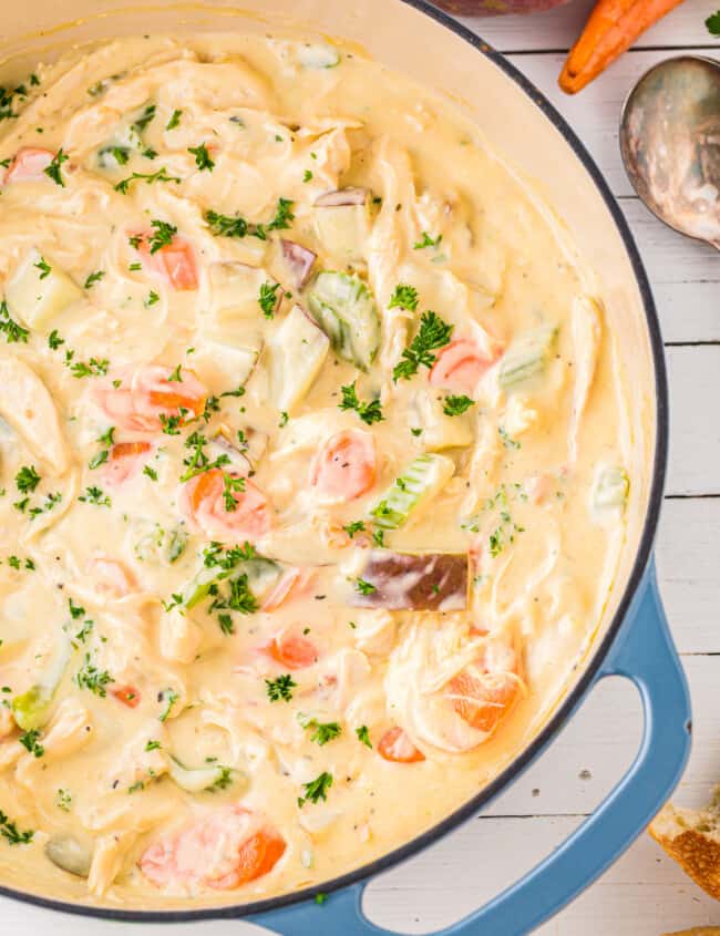 chicken chowder in a blue pot with carrots and bread.