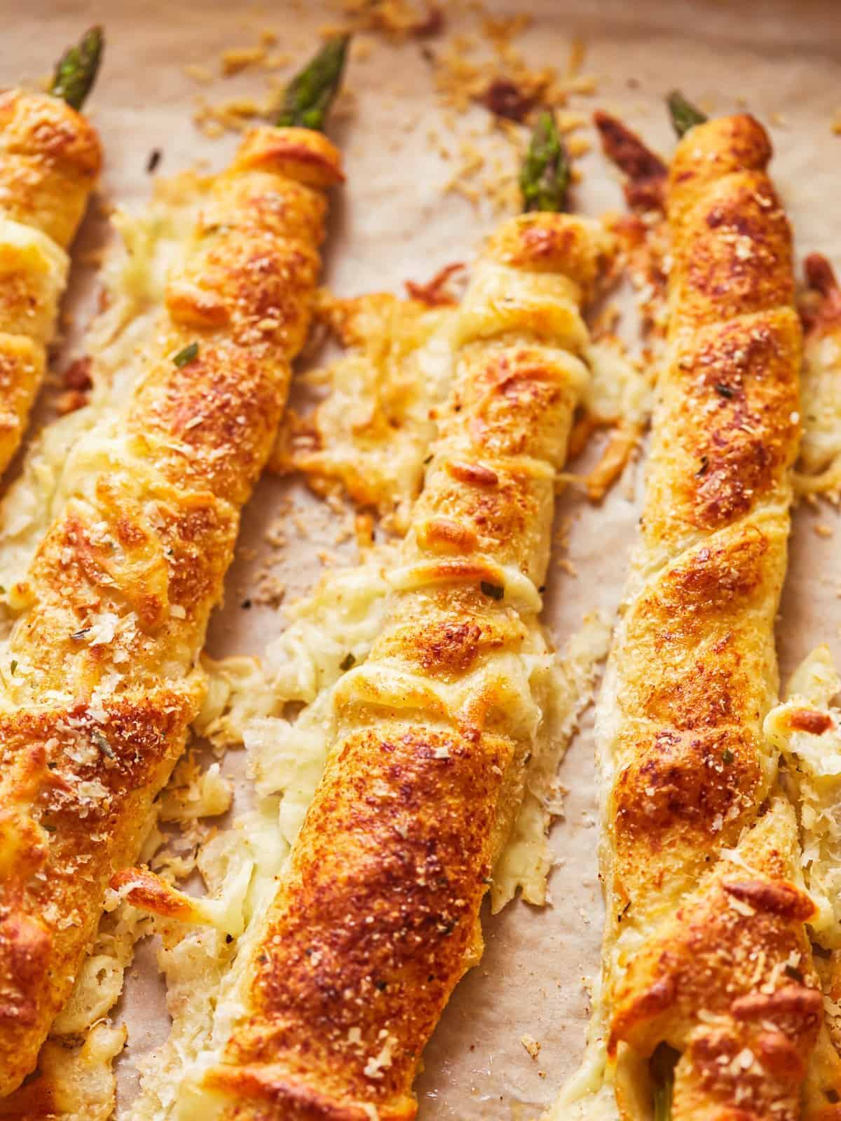 three-quarters view of asparagus crescent rolls pointing north-south on parchment paper.