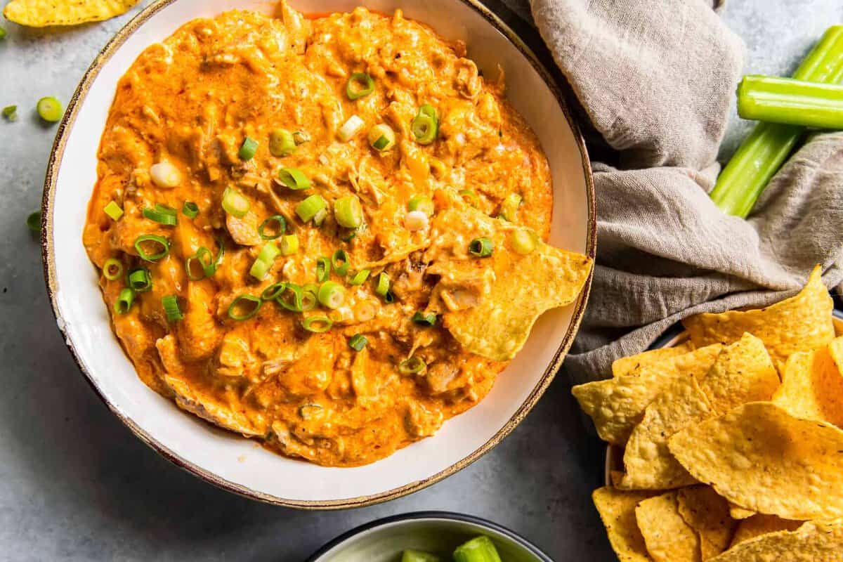 bowl of chips next to crockpot buffalo chicken dip