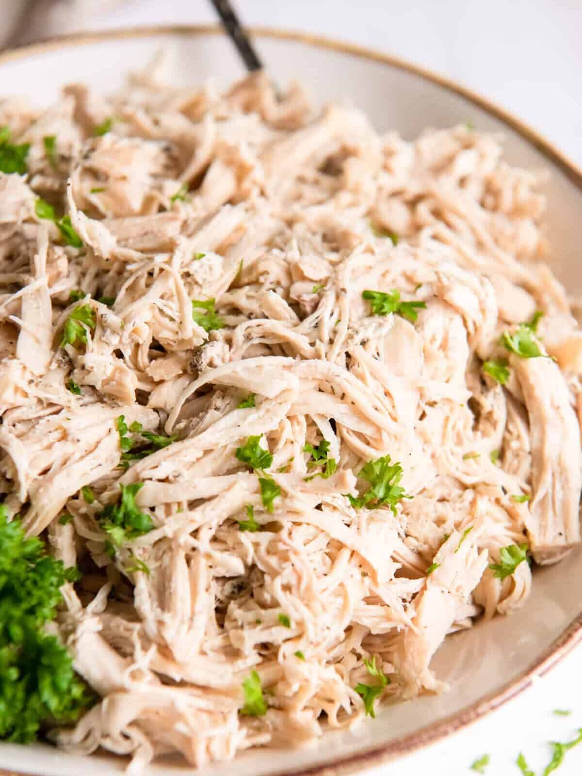 crockpot shredded chicken in a white bowl.