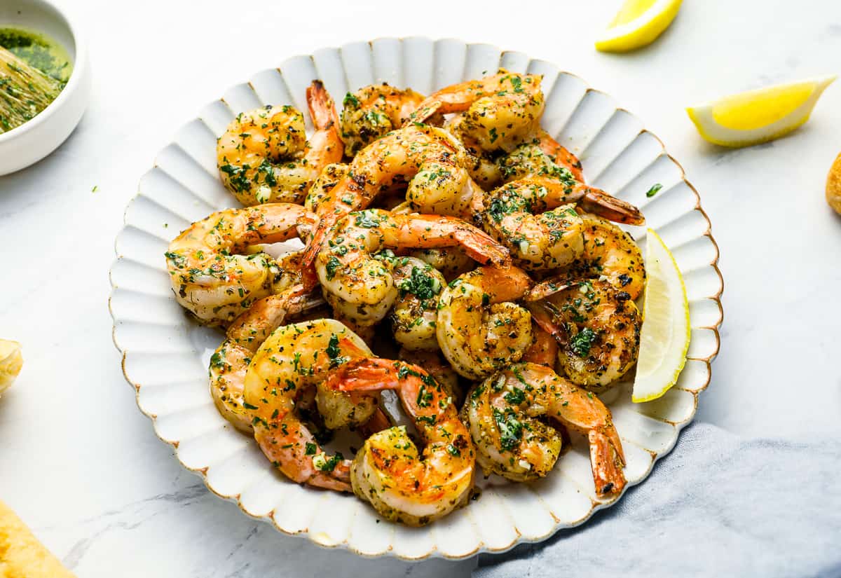 three-quarters view of marinated grilled shrimp on a white plate.