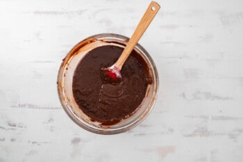 brownie batter in a glass bowl with a wooden spoon.