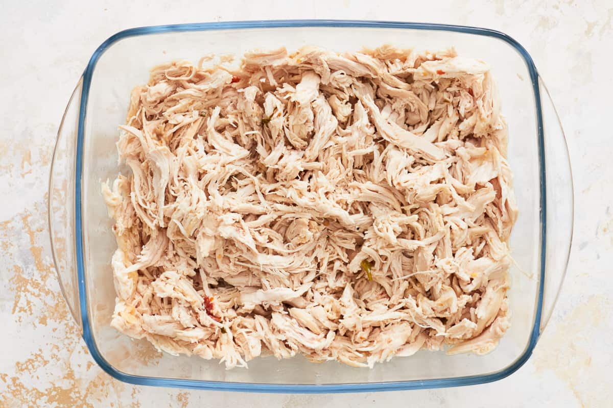 shredded alfredo chicken in a glass baking dish.