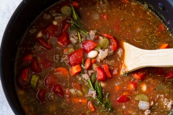 pasta e fagioli soup in a pot with a wooden spoon.