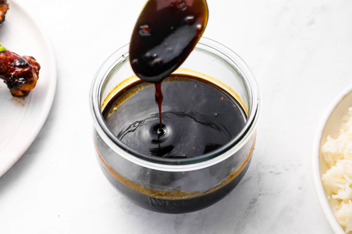 three-quarters view of kbbq sauce being scooped from a glass bowl with a spoon to show the viscosity.